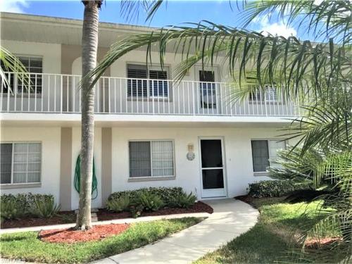 A white building with palm trees in front of it.