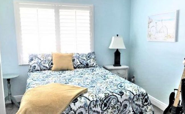 A bedroom with a bed, nightstand and lamp.