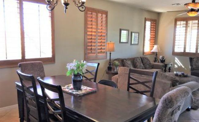 A dining room table with chairs and a vase of flowers.