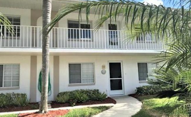 A white building with palm trees in front of it.