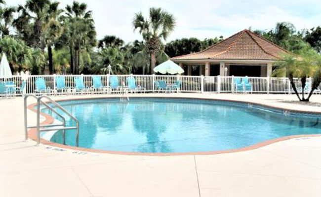 A pool with chairs and umbrellas in the background.
