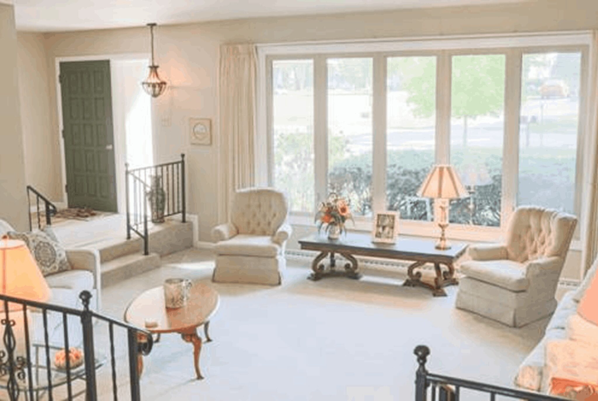 A living room with white furniture and large windows.
